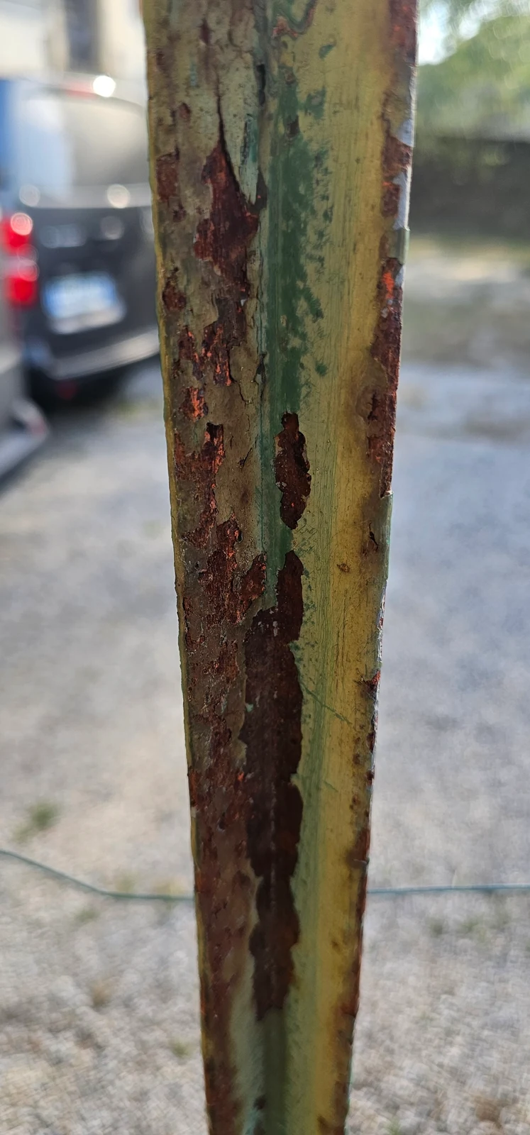 Détail des anciennes couches de peinture et de la corrosion sur un barreau.